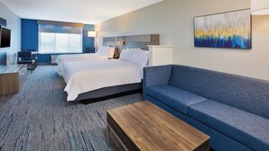 Ein Hotelzimmer mit einem großen Bett, einer Couch, einem Holztisch und einem Fernseher.