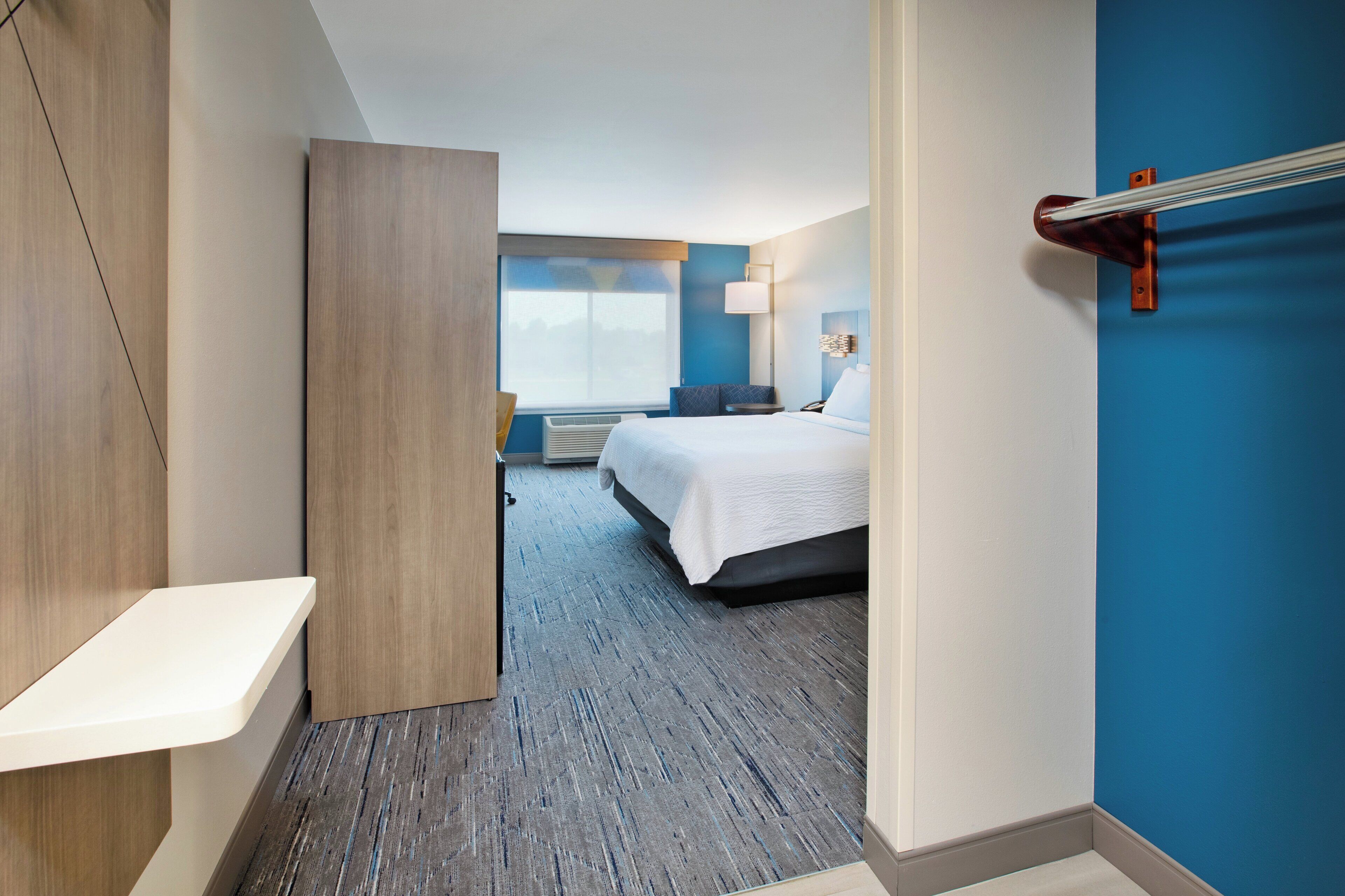 Habitación de hotel con cama, mesita de noche y vistas al exterior.