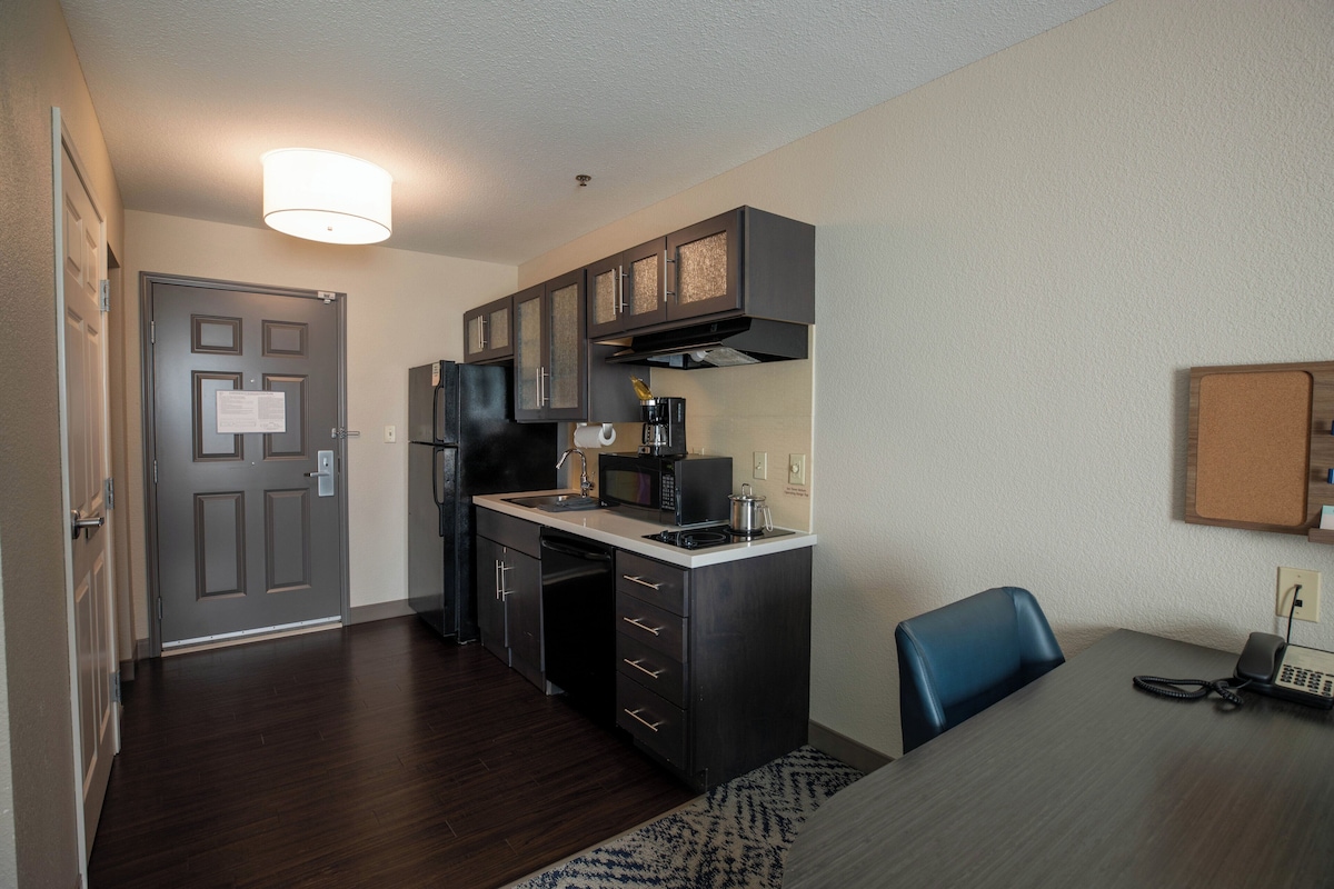A compact kitchen with a refrigerator, microwave, coffee maker, and a small sink.