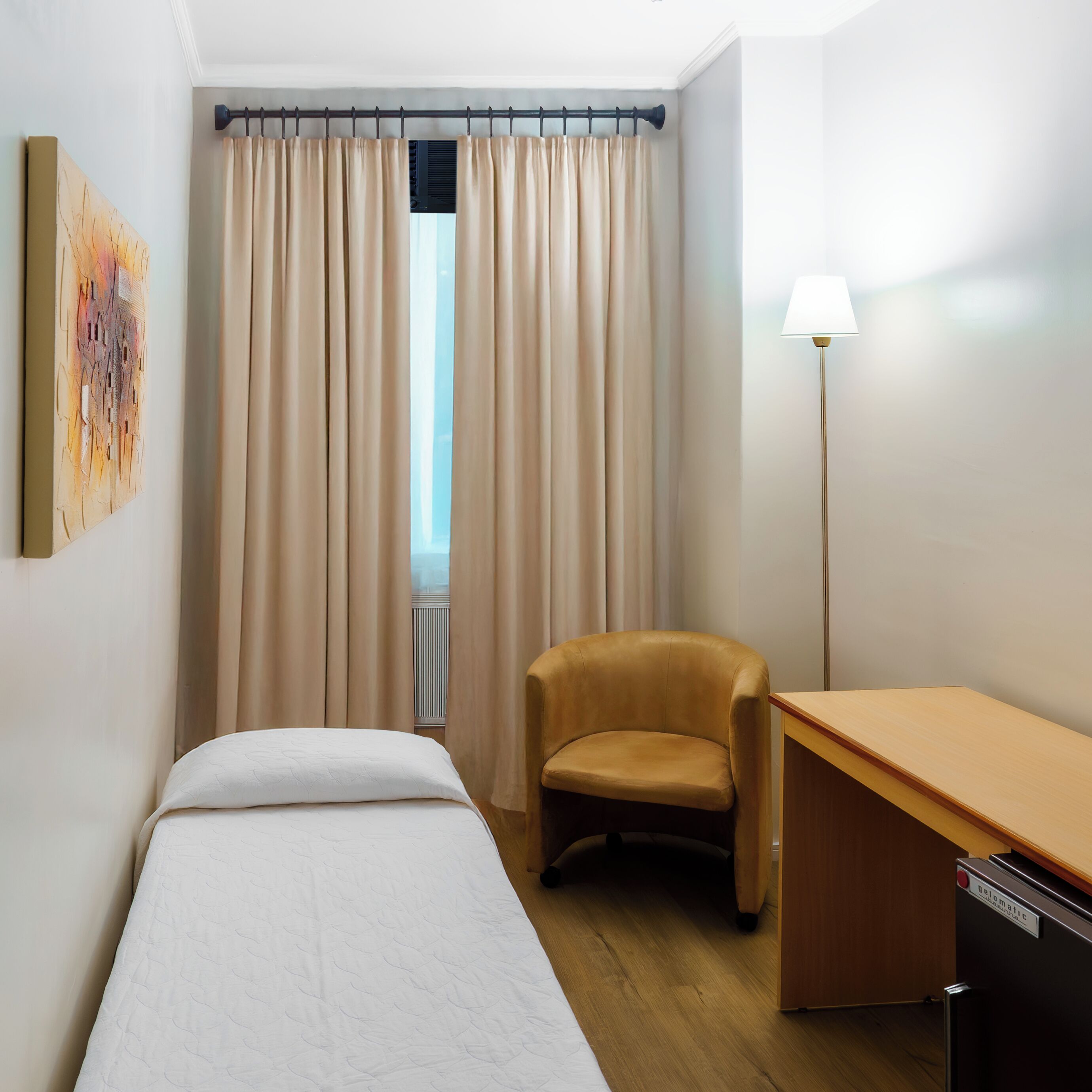 Ein Hotelzimmer mit Bett, Stuhl, Schreibtisch und Lampe.