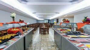 A buffet setup with various food items and a stone-tiled floor. - Hotel Augusta Boulevard (São Paulo)