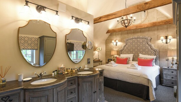 A bedroom with a large bed, two bedside tables, a nightstand, a dresser, and a vanity with a mirror. - Holly Lodge Boutique B&B (Fakenham)