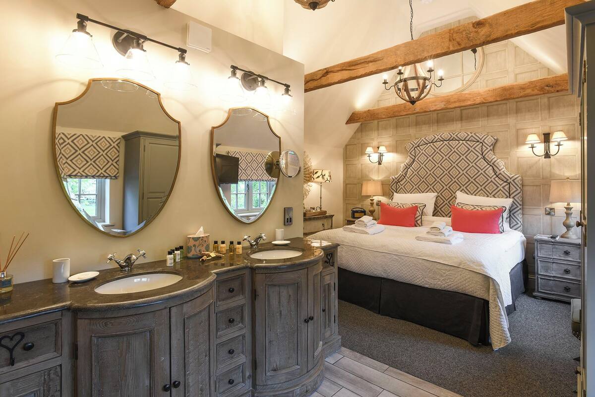 Un dormitorio con una cama grande, dos mesitas de noche, una cómoda y un tocador con espejo.