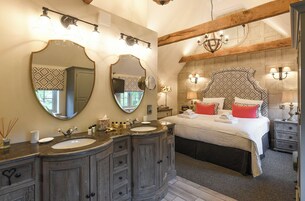 Un dormitorio con una cama grande, dos mesitas de noche, una cómoda y un tocador con espejo.