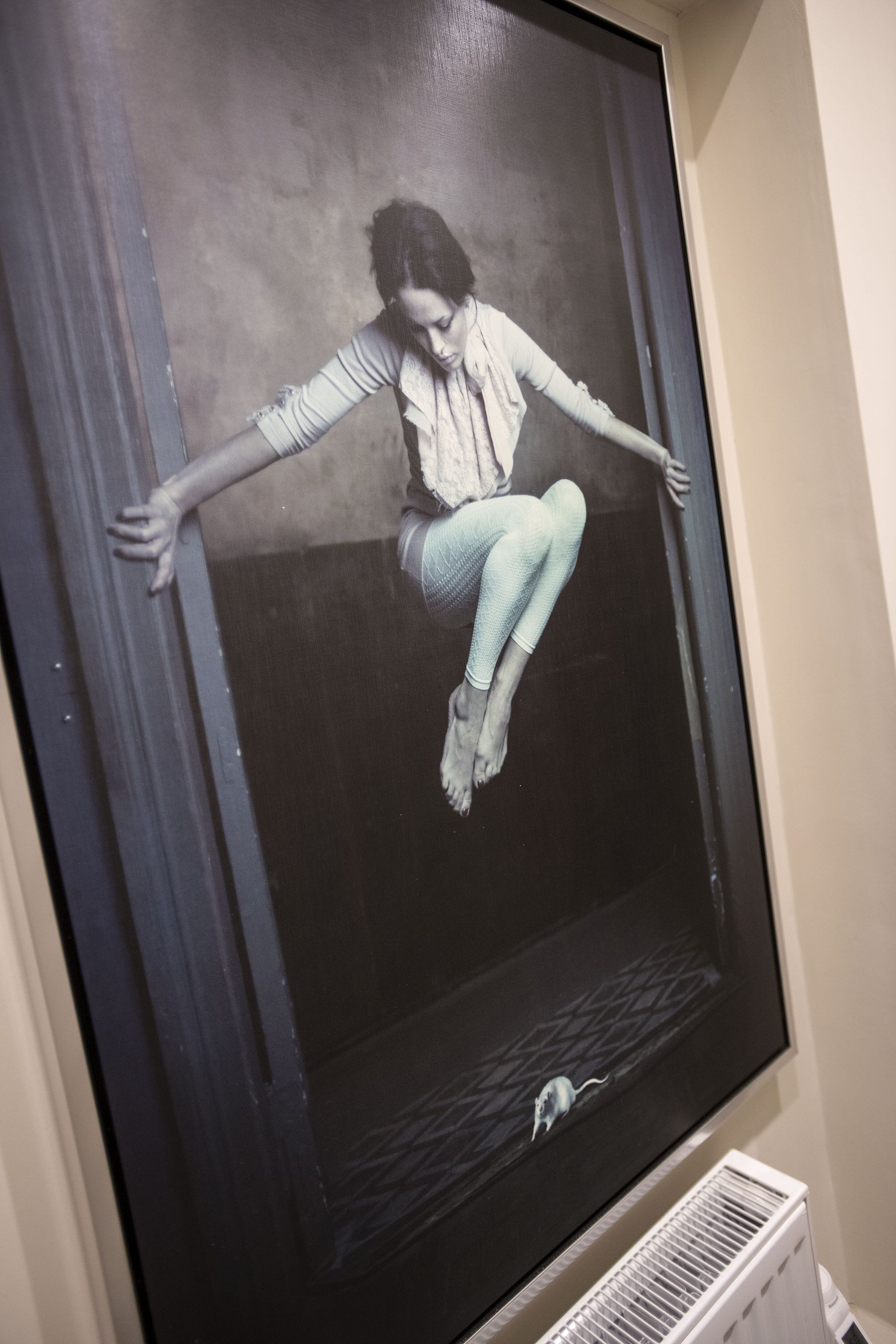 A large framed artwork of a person sitting on a window sill.