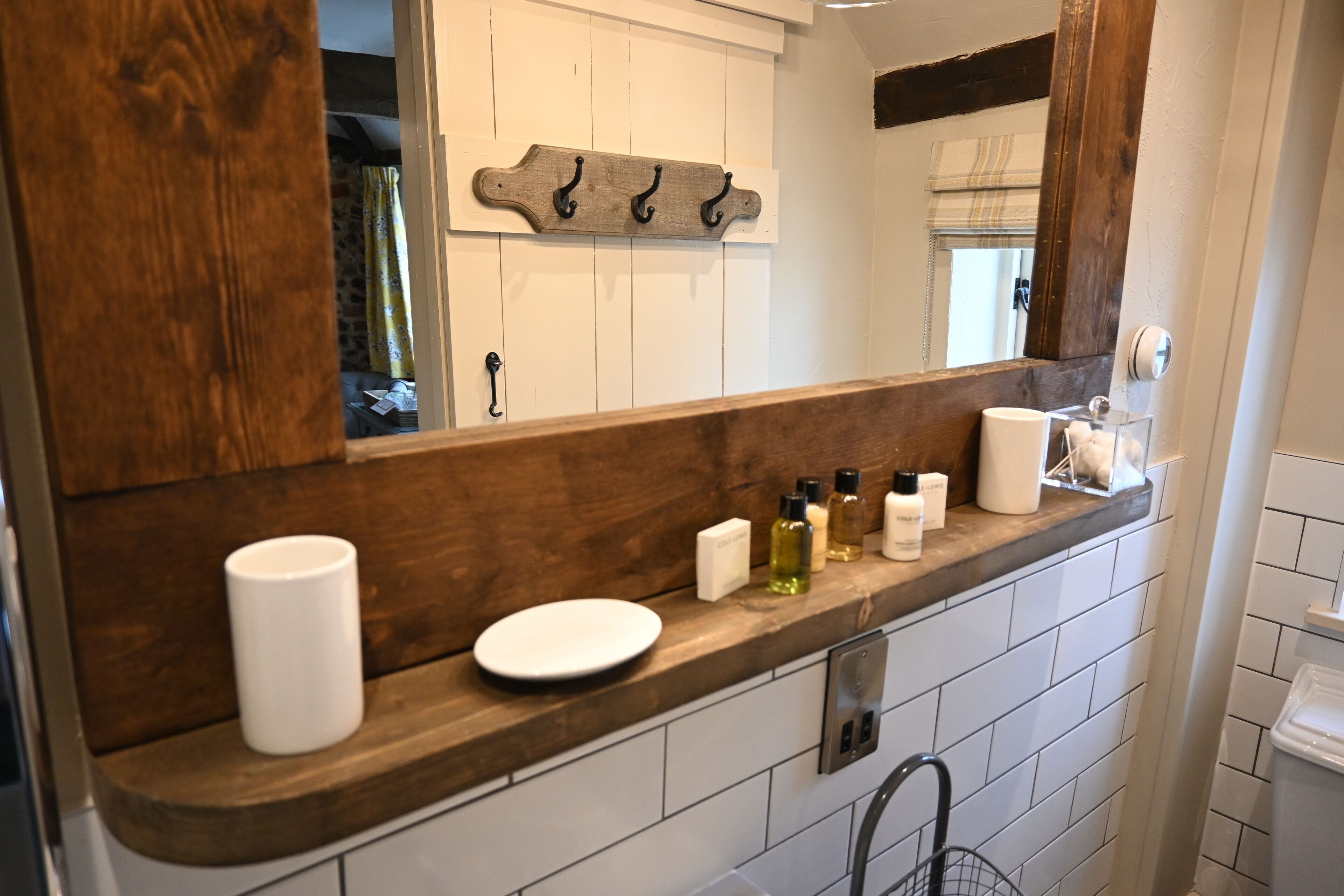 A bathroom with a wooden vanity, a mirror, and a towel rack.