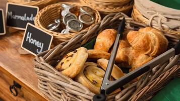 A wicker basket filled with pastries and honey jars, with labels indicating 'Marmalade' and 'Honey'.