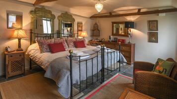 A bedroom with a four-poster bed, a wooden dresser, a wicker chair, and a mirror on the wall.