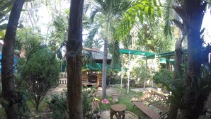 Un jardin tropical avec un banc en bois, une petite table et un kiosque.
