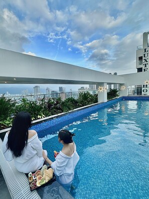 A rooftop pool with a city view, a dining table with food, and a building with 'LUXE' signage. - ViAn Hotel And Spa Da Nang (Da Nang)