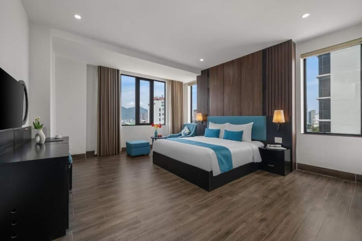 A modern hotel room with a large bed, a desk, and a TV.
