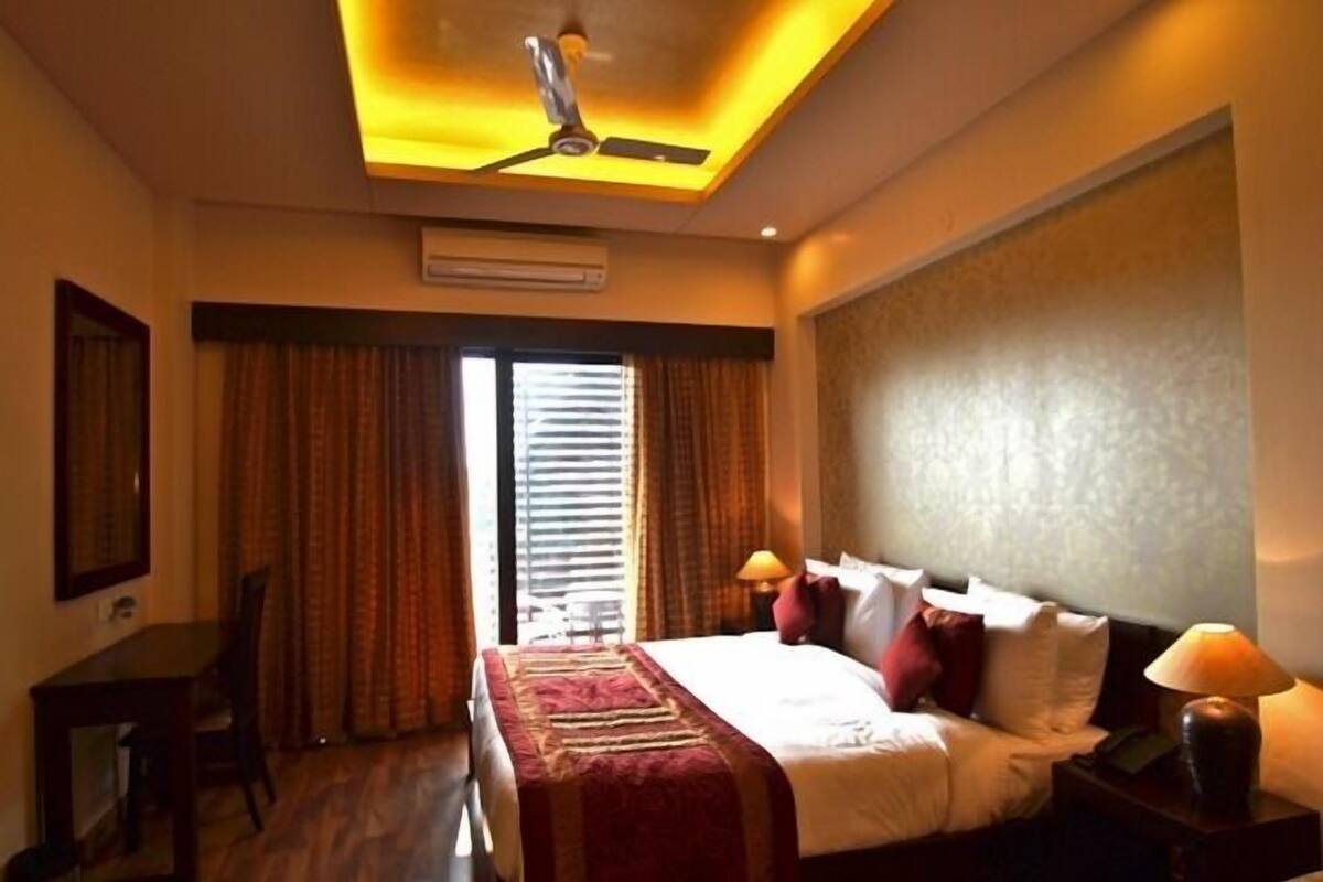 A hotel room with a bed, bedside tables, a desk, and a ceiling fan.