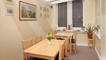 A dining area with a wooden table and chairs, a vase with flowers, and a window with a view.