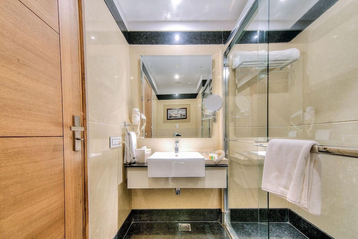 A modern bathroom with a glass shower enclosure, a white sink, and a large mirror.