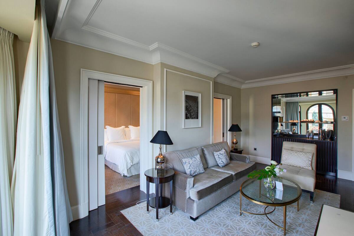 A hotel room with a bed, a sofa, a coffee table, and a mirror.