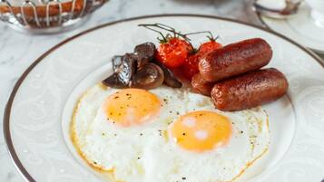 Una mesa de mármol con huevos, salchichas y una variedad de frutas y productos de pastelería para el desayuno.
