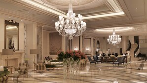 A luxurious lobby with a grand chandelier, plush seating, and a polished marble floor.