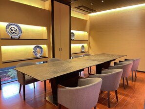 A modern dining area with a long table and six chairs, wooden paneling, and decorative plates on shelves. - Hotel Garden Palace & Kansai Airport Spa (Izumisano)