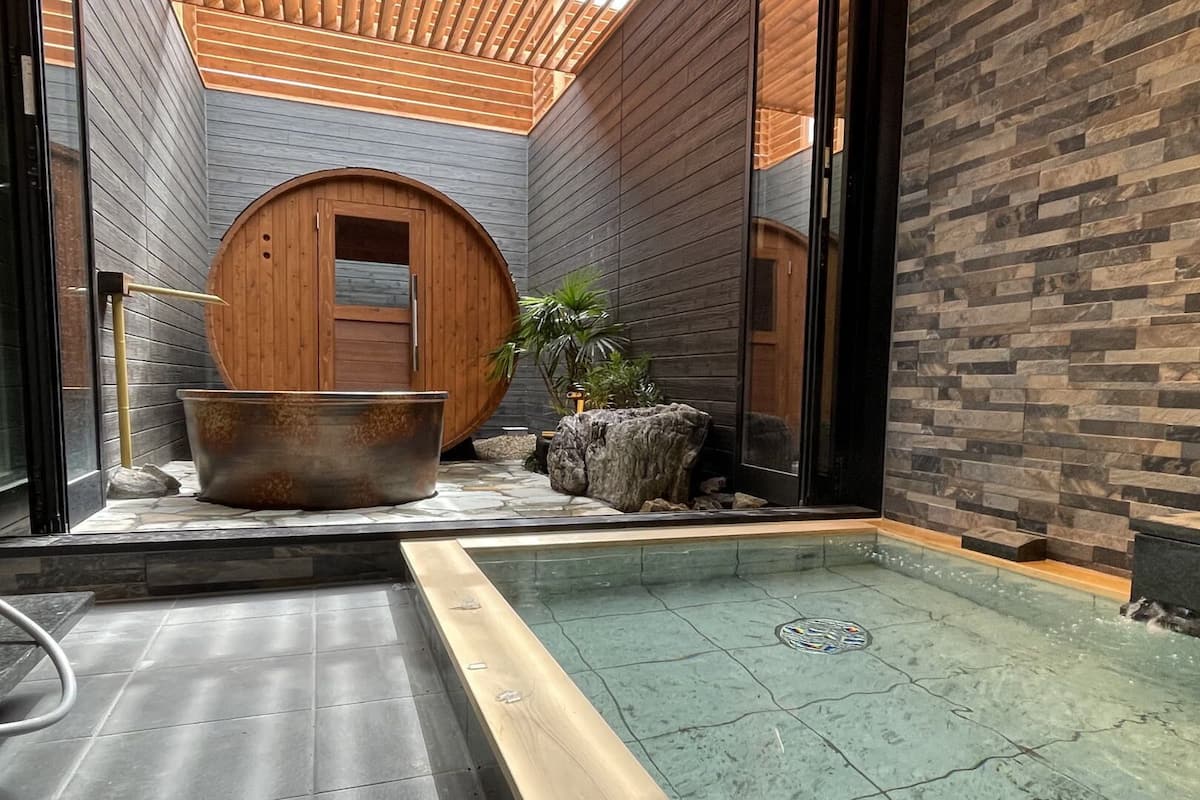 Ein Wellnessbereich mit Steinboden, einer Holztonne und einer Steinwand.