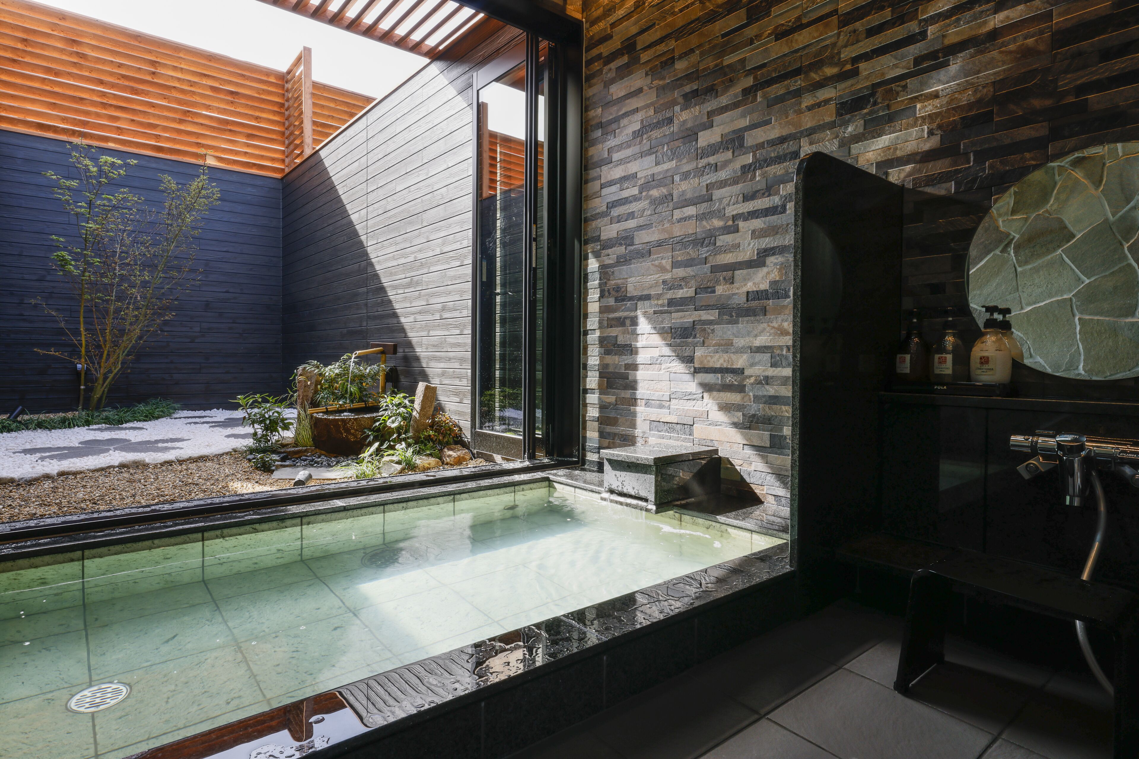 A modern bathroom with a glass-enclosed shower, a stone-tiled floor, and a built-in bench.