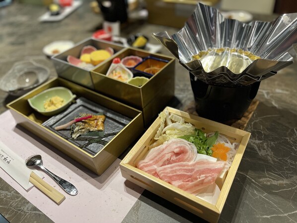 A table with various food items in wooden boxes, including sashimi and vegetables.