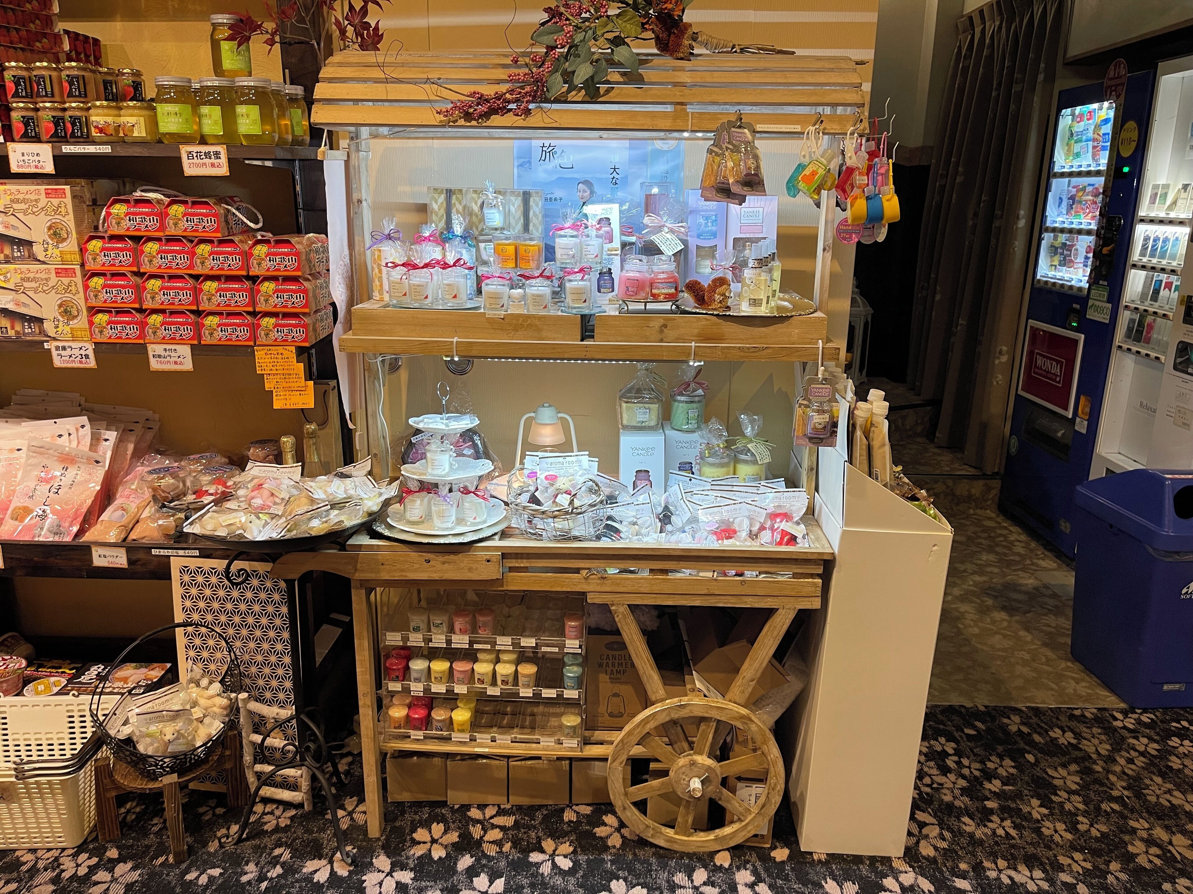 Una exhibición de diversos productos envasados, incluyendo alimentos y productos de cuidado personal, organizados sobre un soporte de madera con un frente de vidrio.
