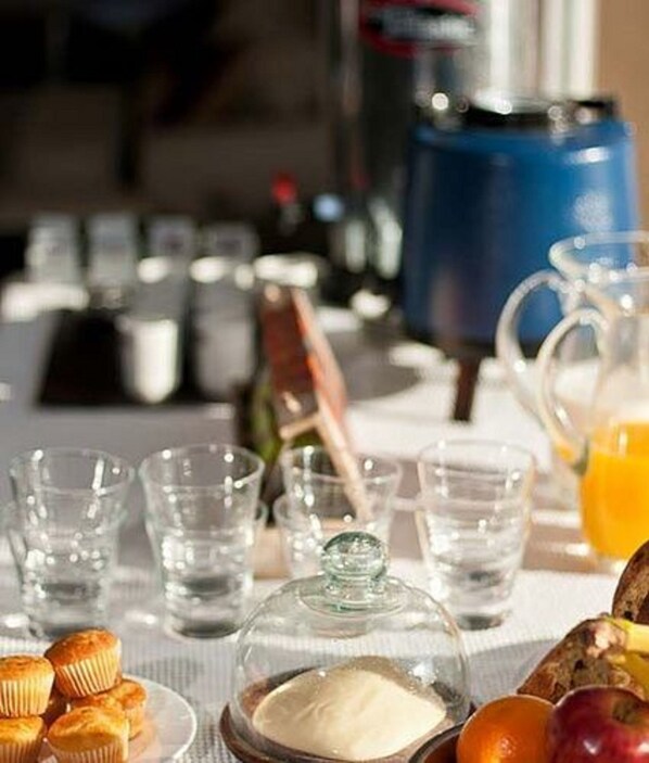 A breakfast table with various food items, glasses, and a coffee maker.