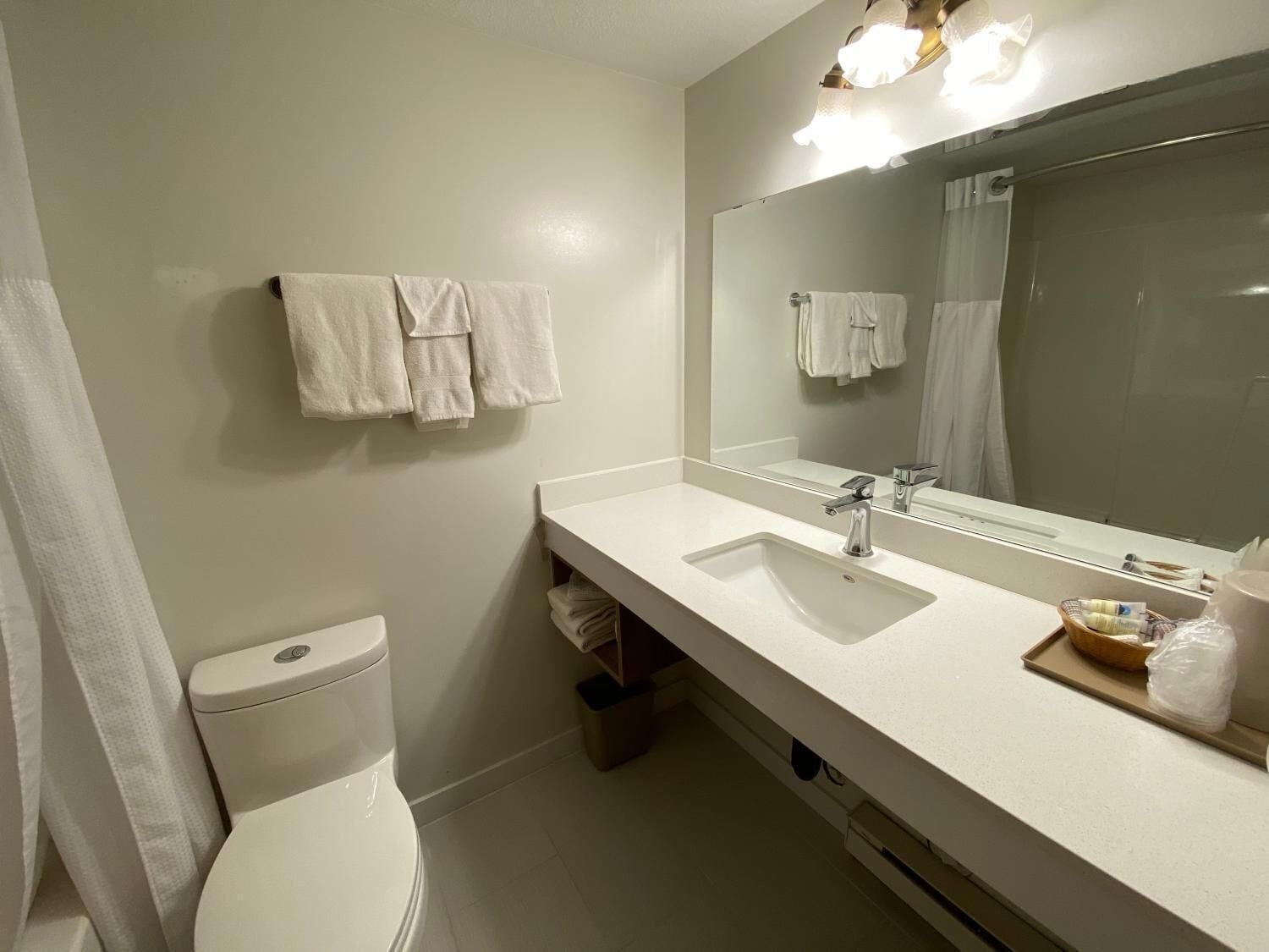 A modern bathroom with a white sink, a mirror, and a toilet.