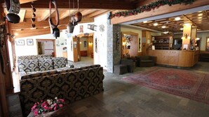 Un'ampia hall con un divano decorato, una reception in legno e una parete in pietra.