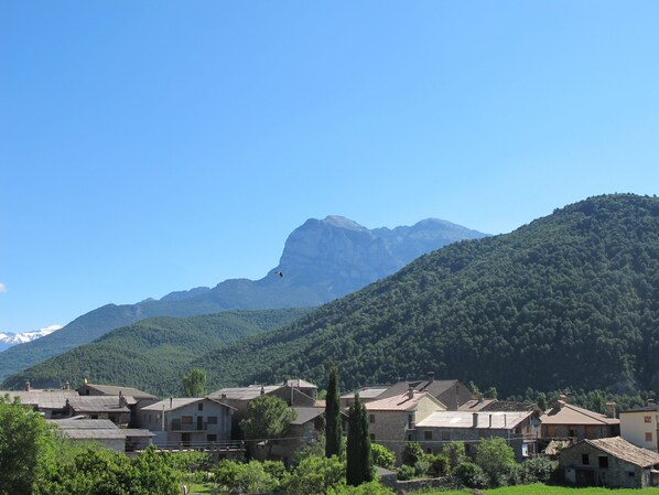 A village with stone buildings, a mountain in the background, and a clear sky.