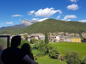 A view of a village with stone buildings and a mountain in the background.