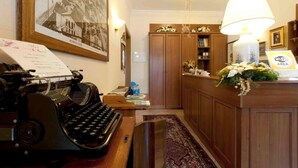 A hotel reception area with a vintage typewriter, a framed photograph, wooden cabinets, a desk with a lamp, and a sign indicating a WiFi area. - Hotel Ristorante ai Campi Di Marcello (Monfalcone)