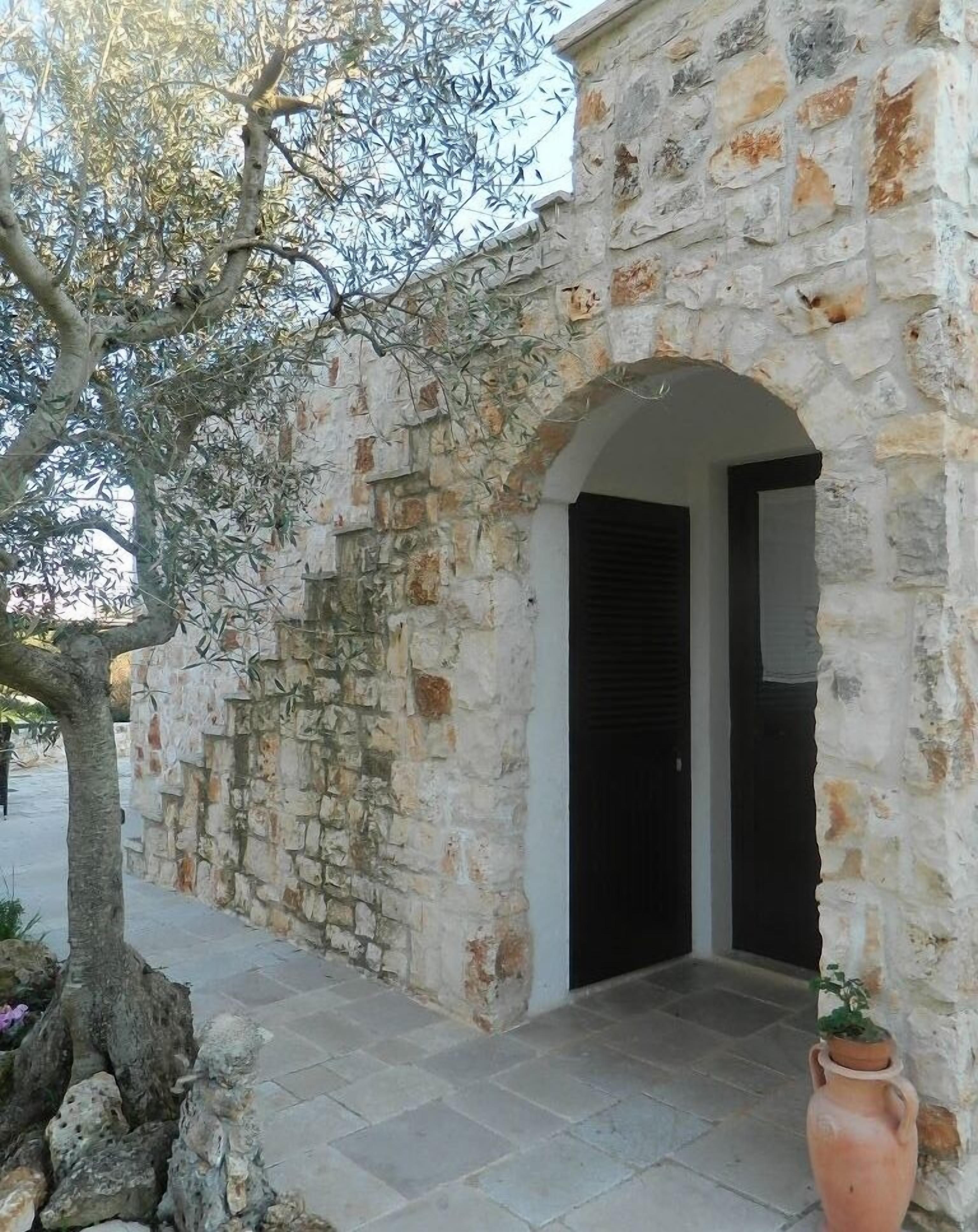 Un edificio in pietra con un ingresso ad arco e una pianta in vaso.