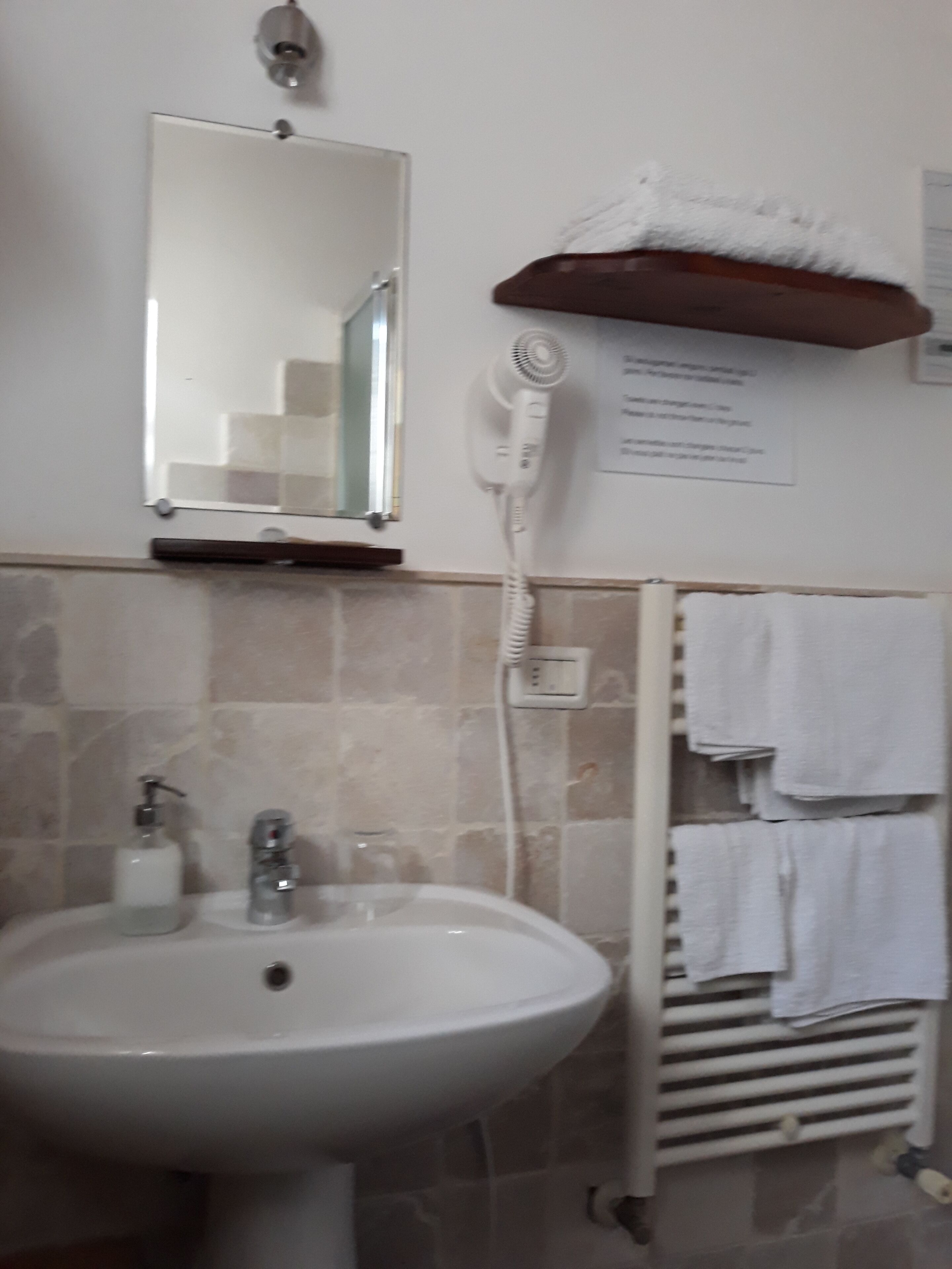 Une salle de bain équipée d’un lavabo, d’un miroir, d’un porte-serviettes et d’un sèche-cheveux.
