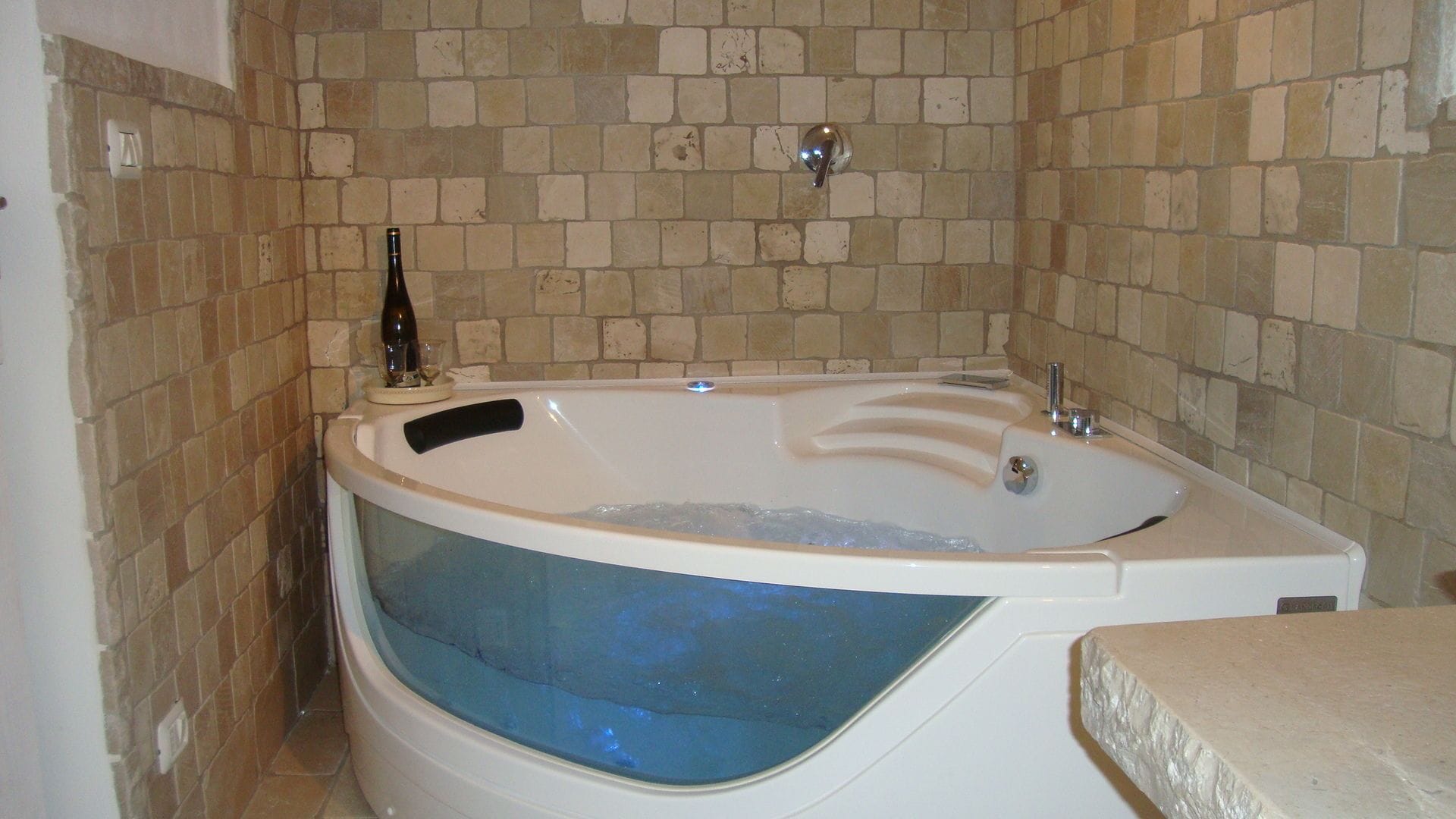 Un baño con una bañera independiente, ducha con mampara de vidrio y pared revestida de azulejos.