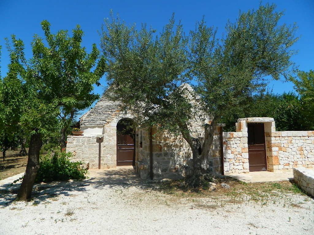 Un edificio de piedra con dos puertas y un árbol en primer plano.
