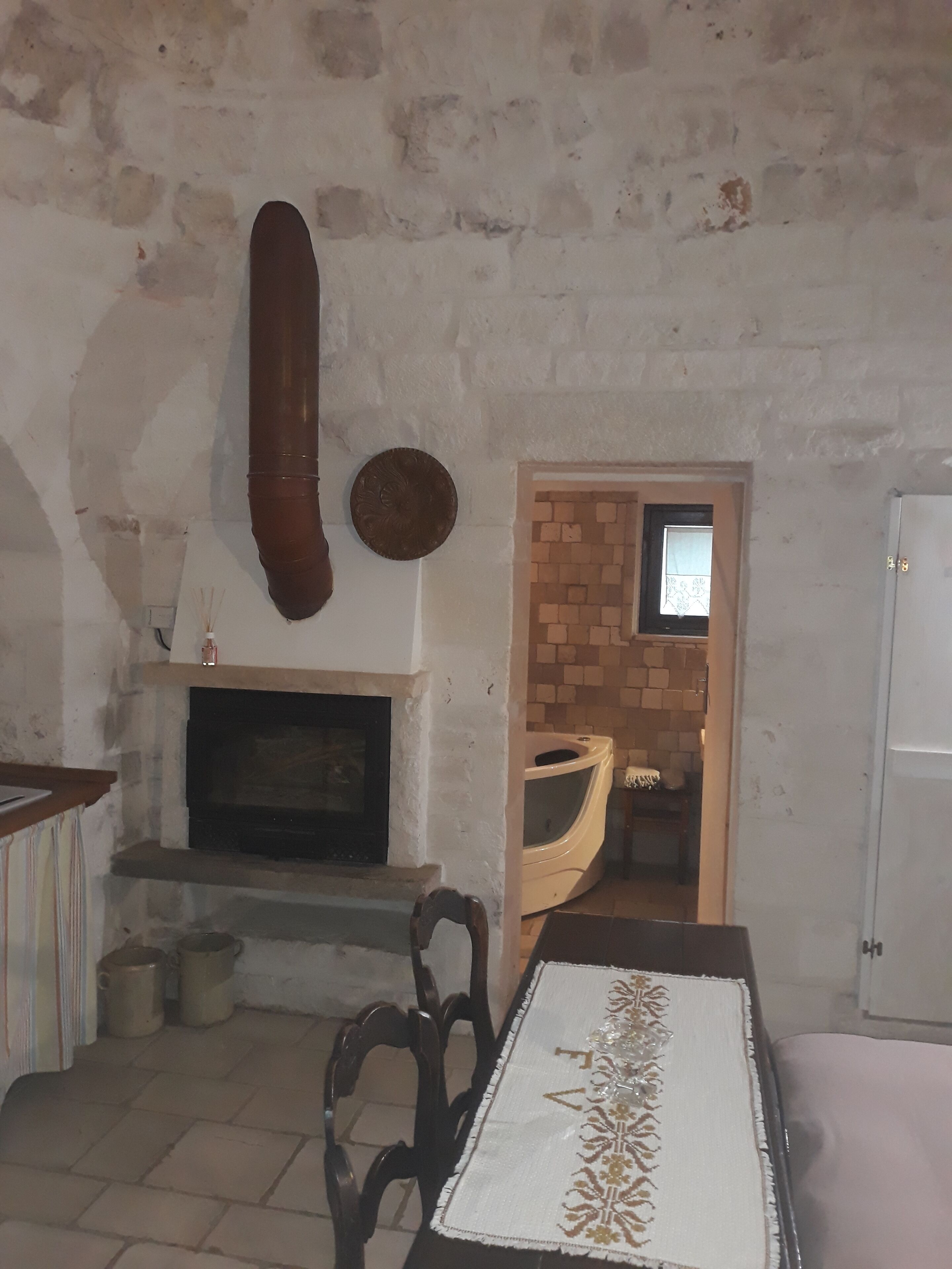 Una habitación con chimenea, una mesa de madera con mantel blanco y una pared de ladrillo.