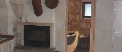 Una habitación con chimenea, una mesa de madera con mantel blanco y una pared de ladrillo.