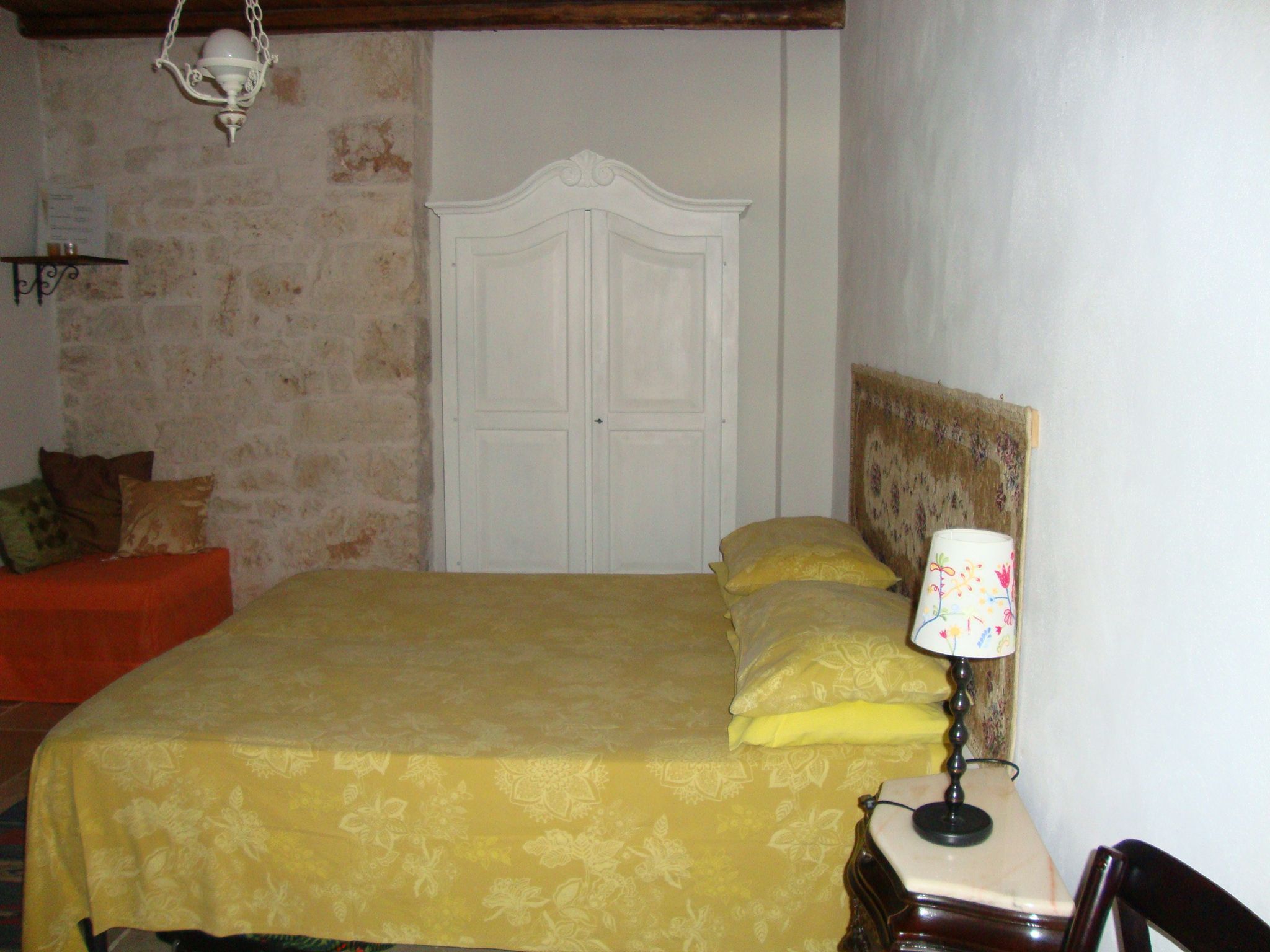 Un dormitorio con cama, mesita de noche, lámpara, cabecero de madera y una puerta.