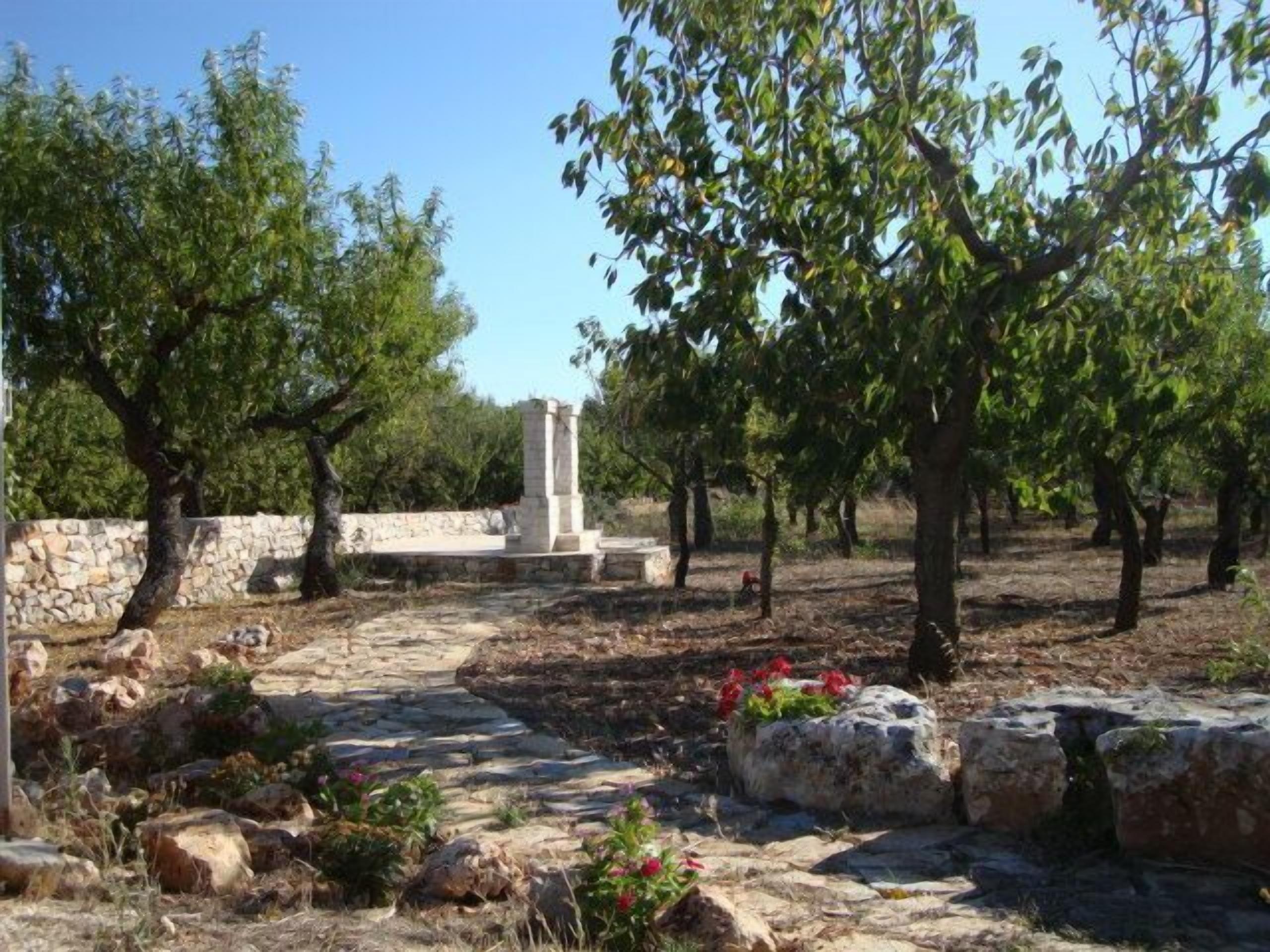 An outdoor area with stone structures, trees, and a clear sky.