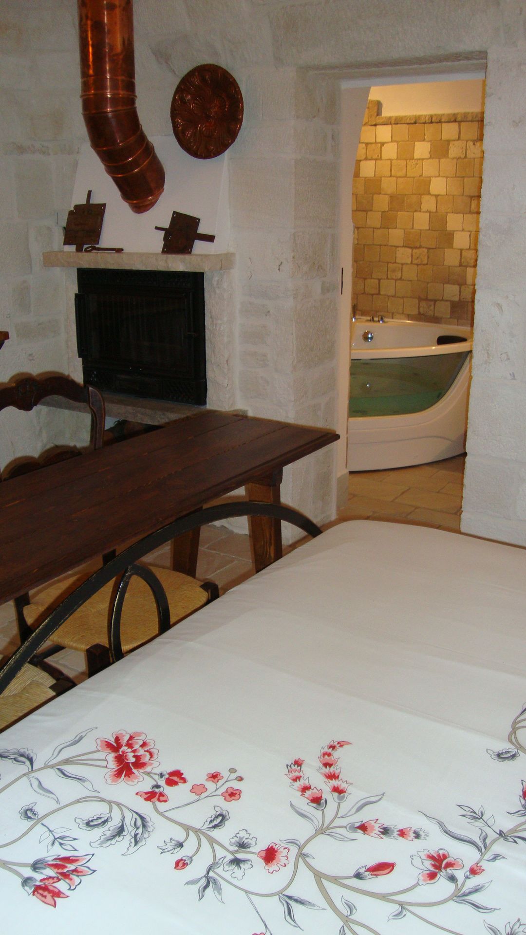 Una habitación con una mesa de madera, chimenea, pared de ladrillo y una bañera.
