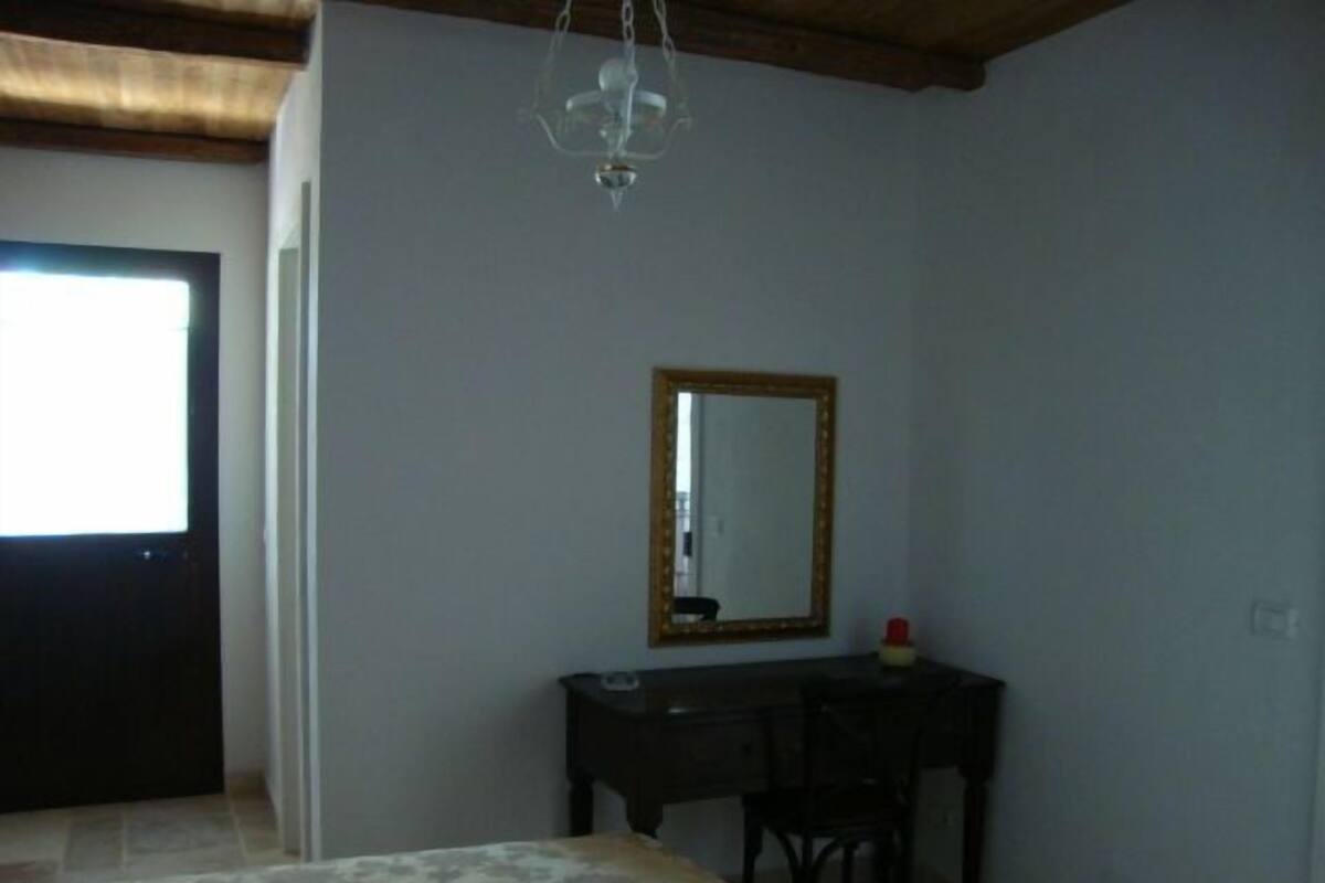 Un dormitorio con cama, escritorio, silla y espejo.