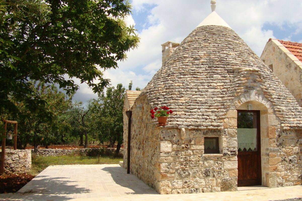 Un edificio de piedra con techo cónico, puerta de madera y una ventana pequeña.
