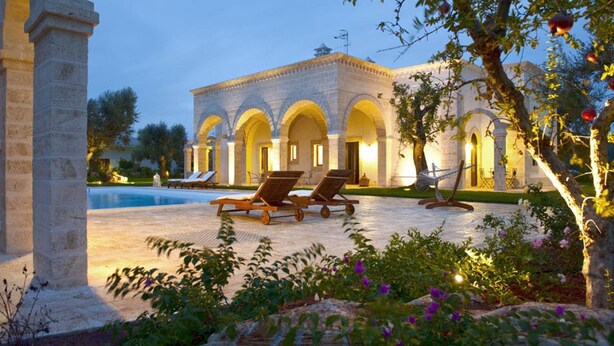 A historic building with arched windows and a pool area with lounge chairs. - Dimora Donna Lucrezia (Fasano)