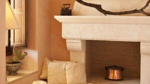 A cozy room with a stone fireplace, two wicker chairs, a cactus, and a lamp. - Dimora Donna Lucrezia (Fasano)