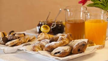 Une table avec des pâtisseries, un pot de confiture et deux verres de jus d’orange.