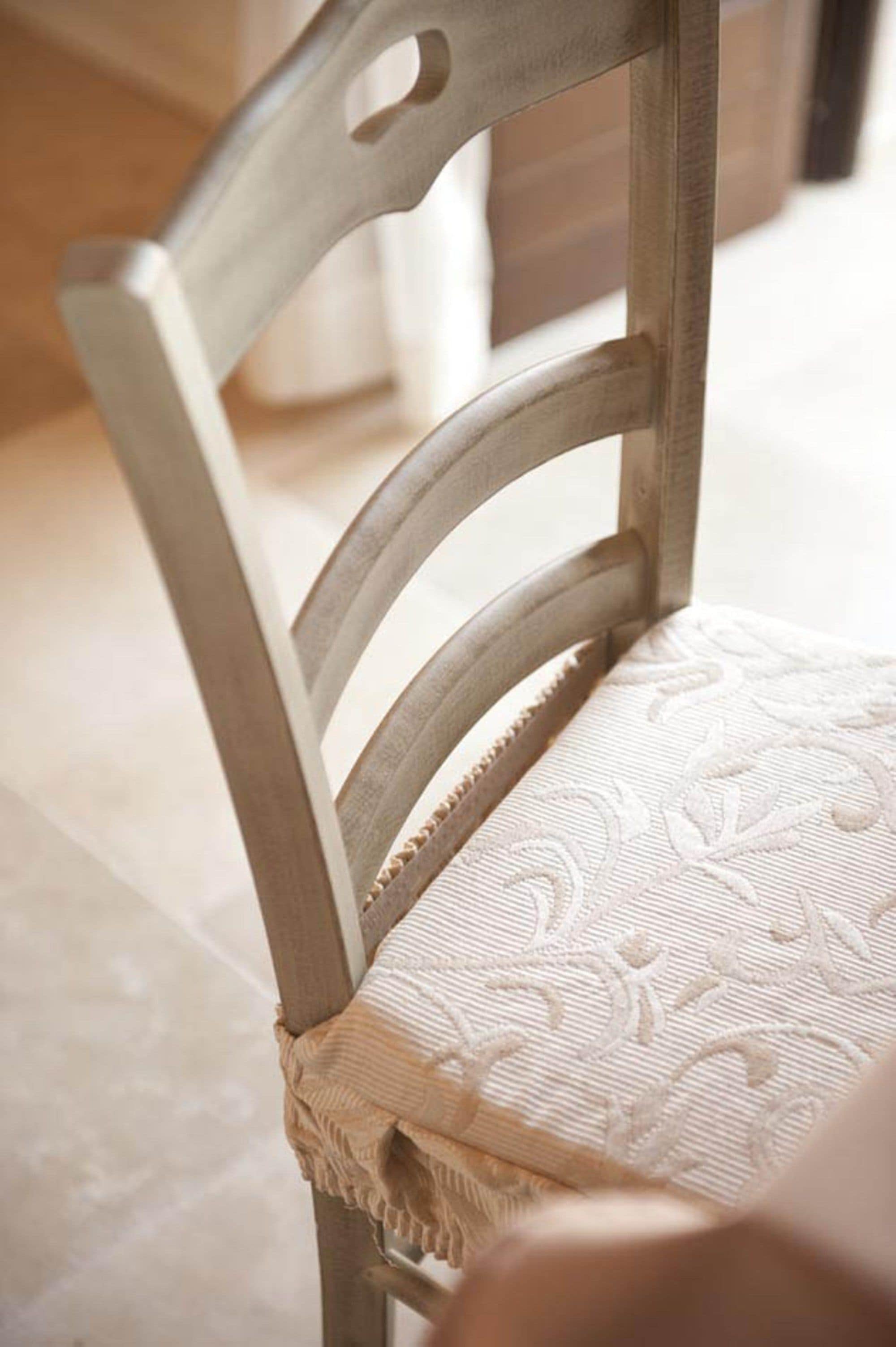 A close-up of a wooden chair with a cushioned seat and a decorative cushion.