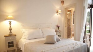 A neatly made bed with white linens and pillows, a bedside lamp, and a small bedside table with a lamp. - Dimora Donna Lucrezia (Fasano)