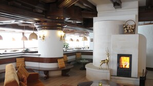 Un espacio lounge acogedor con chimenea, asientos cómodos y vistas al exterior.