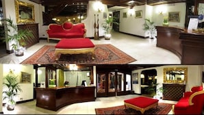 Un hall de hotel con un sofá rojo, un mostrador de recepción y un espejo grande.